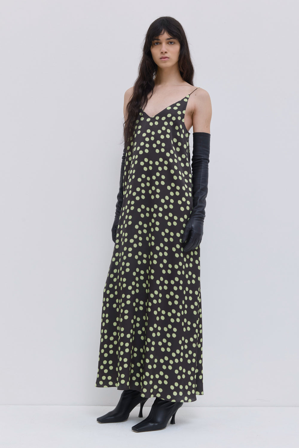 Side view of a dark forest penny A-line dress with thin shoulder straps, V-neck and all-over dot print by Christian Wijnants.