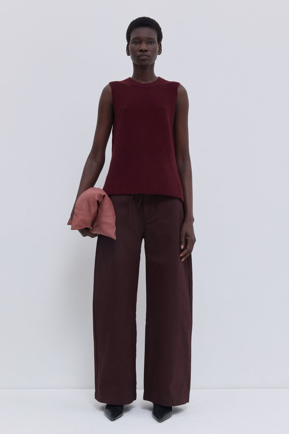 Garnet sleeveless wholegarment knit top with round neckline and side slits.