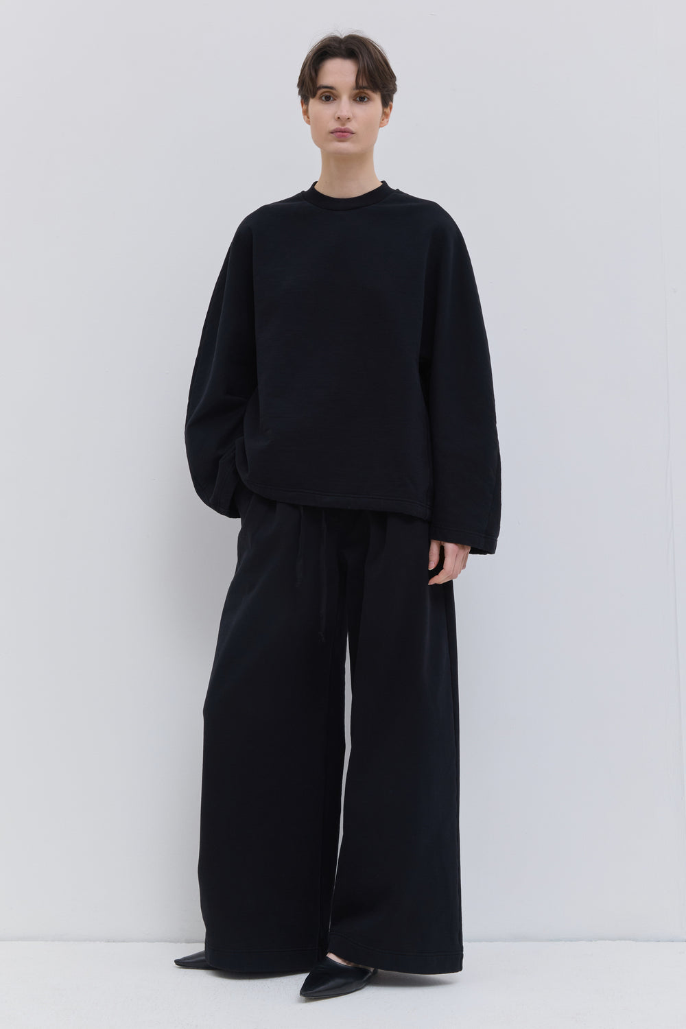 Front view of black wide-leg jersey sweatpants with drawstring waist.